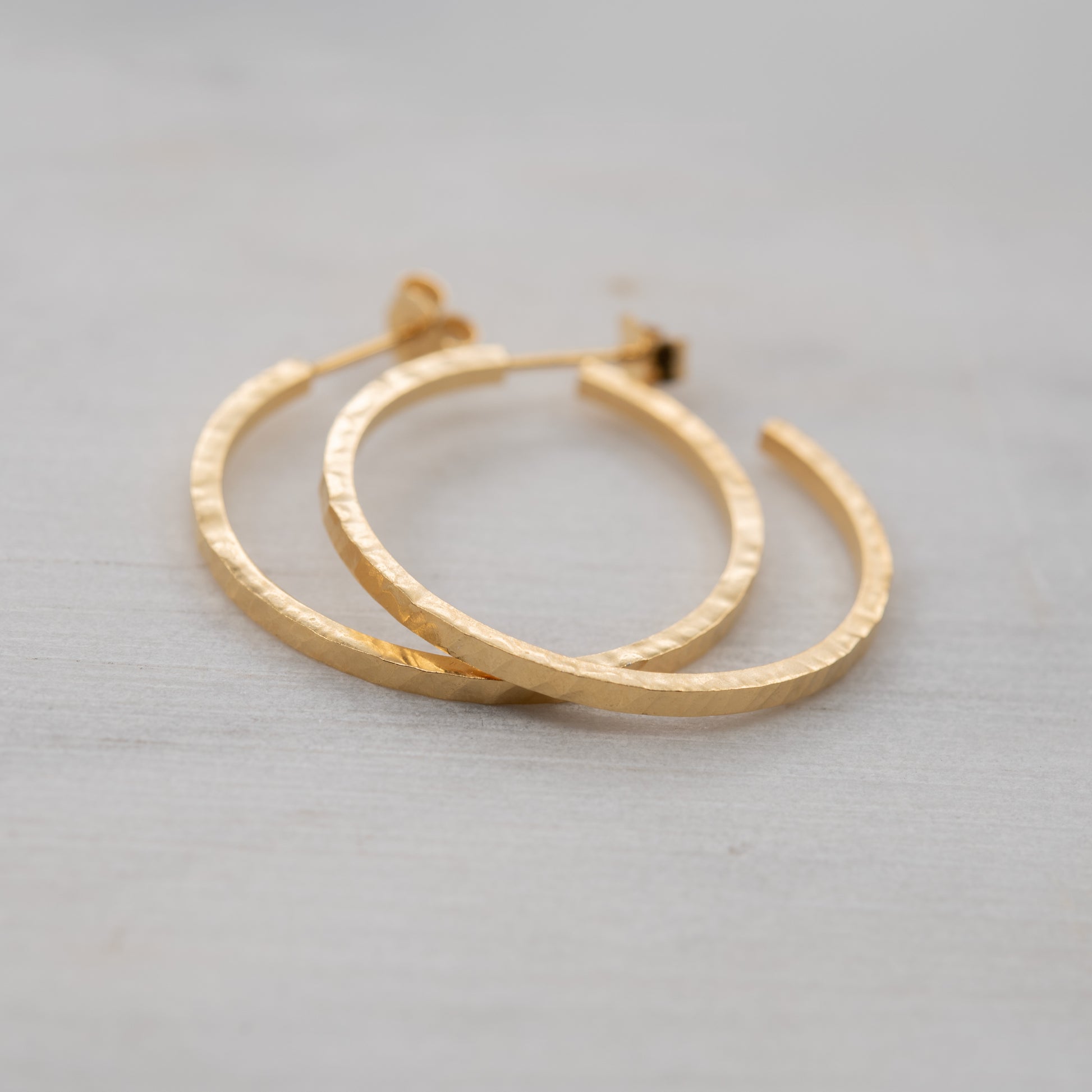 Hammered gold hoop earrings on white background – handcrafted Paris jewelry