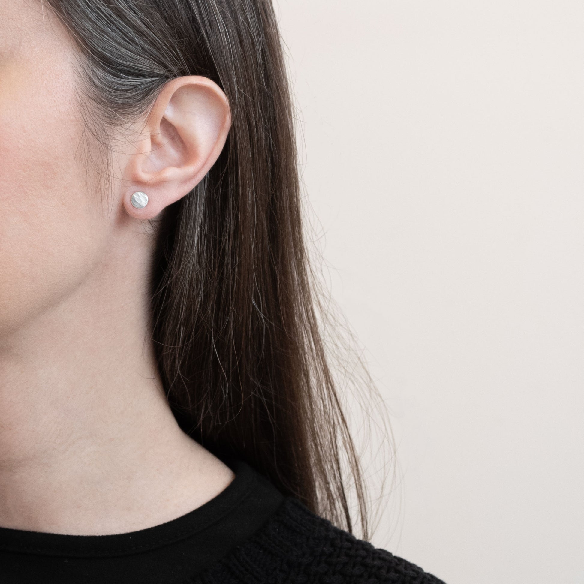 Model wearing mismatched hammered silver stud earrings, highlighting their minimalist and organic design. Perfect for everyday wear with a natural, handcrafted touch.