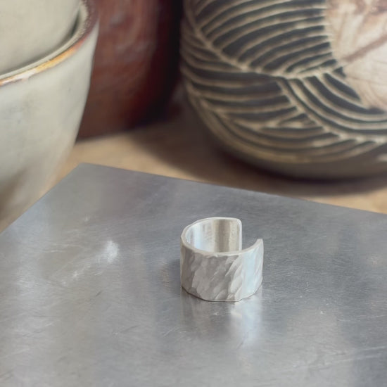 Bague d’oreille en argent massif 925 martelé, présentée à la main dans l’atelier pour montrer sa forme, son ouverture et sa texture.