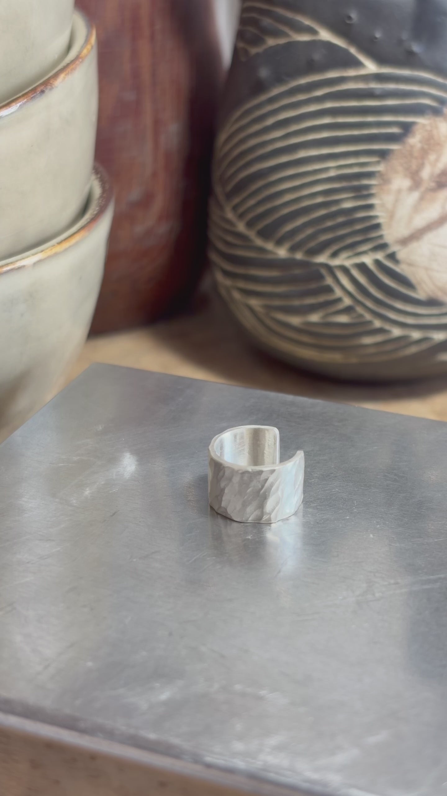 Bague d’oreille en argent massif 925 martelé, présentée à la main dans l’atelier pour montrer sa forme, son ouverture et sa texture.