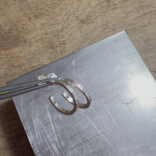 Petites créoles martelées en argent massif 925, présentées à la main puis portées à l’oreille pour montrer leur taille et leur texture artisanale.