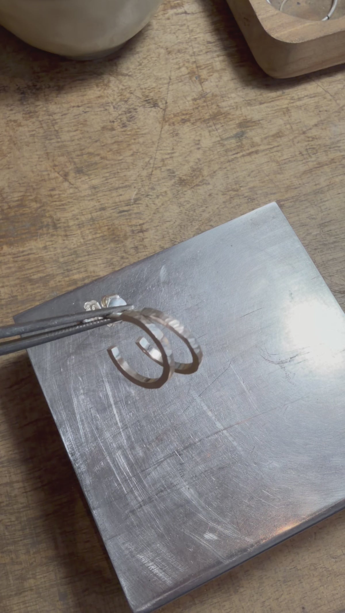 Petites créoles martelées en argent massif 925, présentées à la main puis portées à l’oreille pour montrer leur taille et leur texture artisanale.