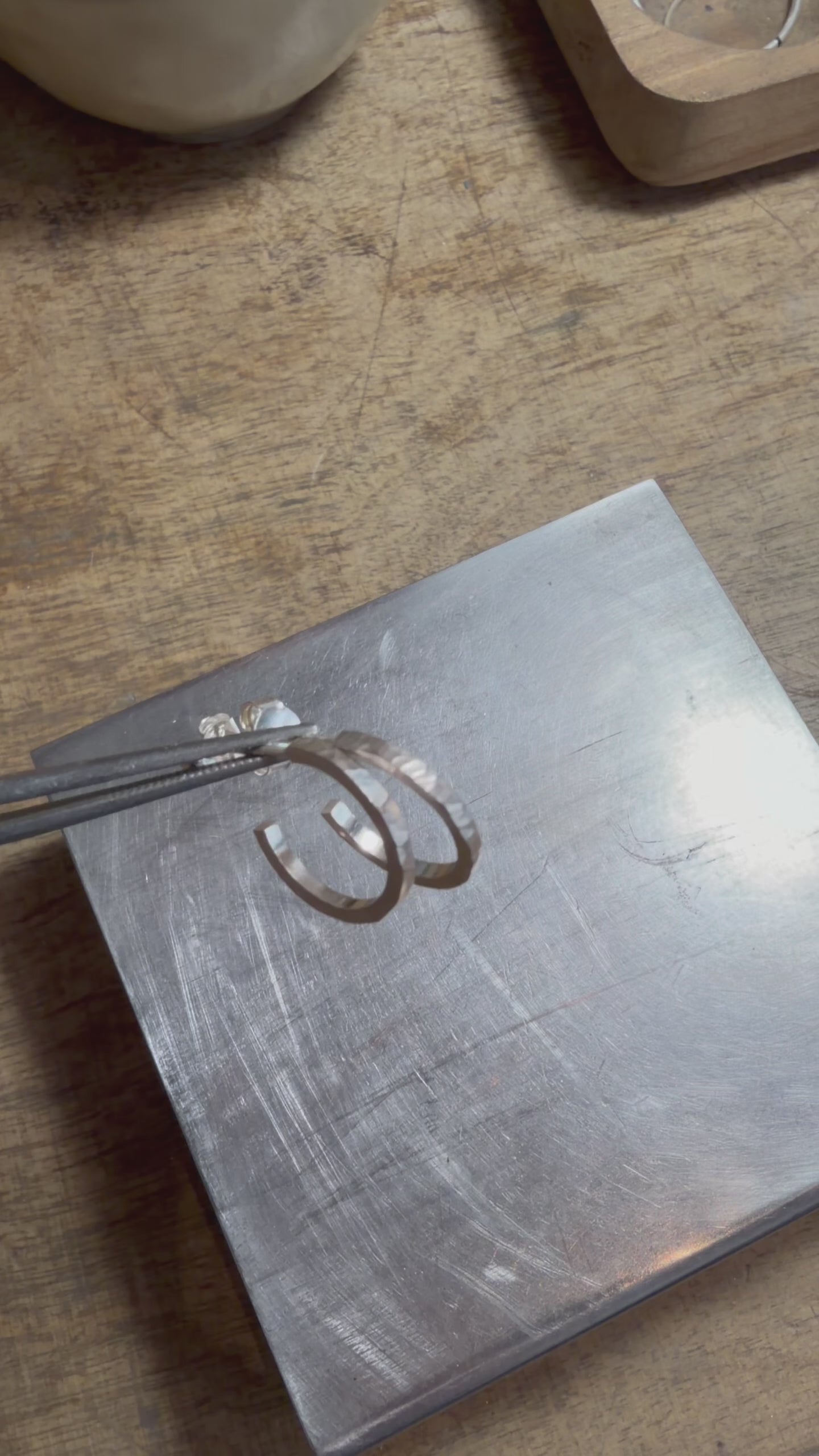 Petites créoles martelées en argent massif 925, présentées à la main puis portées à l’oreille pour montrer leur taille et leur texture artisanale.