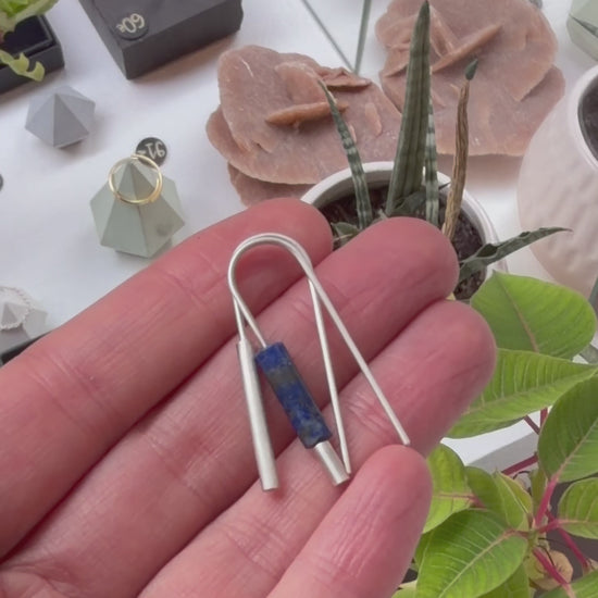 Boucles d’oreilles dépareillées en argent massif 925 et lapis-lazuli, présentées à la main pour montrer leurs détails et leurs proportions.