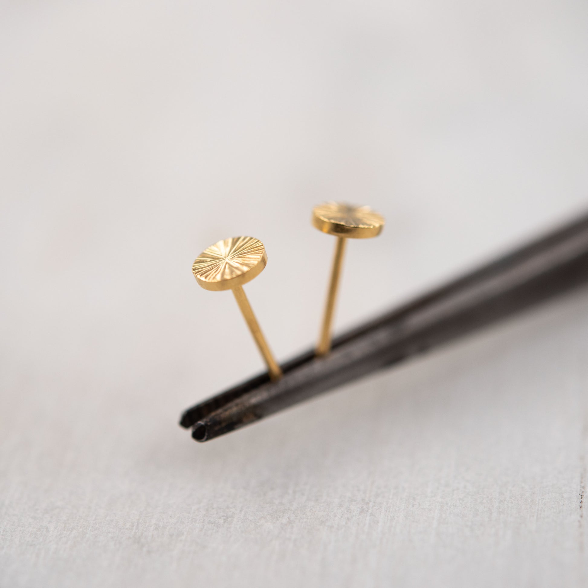 Close-up of small gold vermeil engraved stud earrings on white background – minimalist Paris handmade jewelry