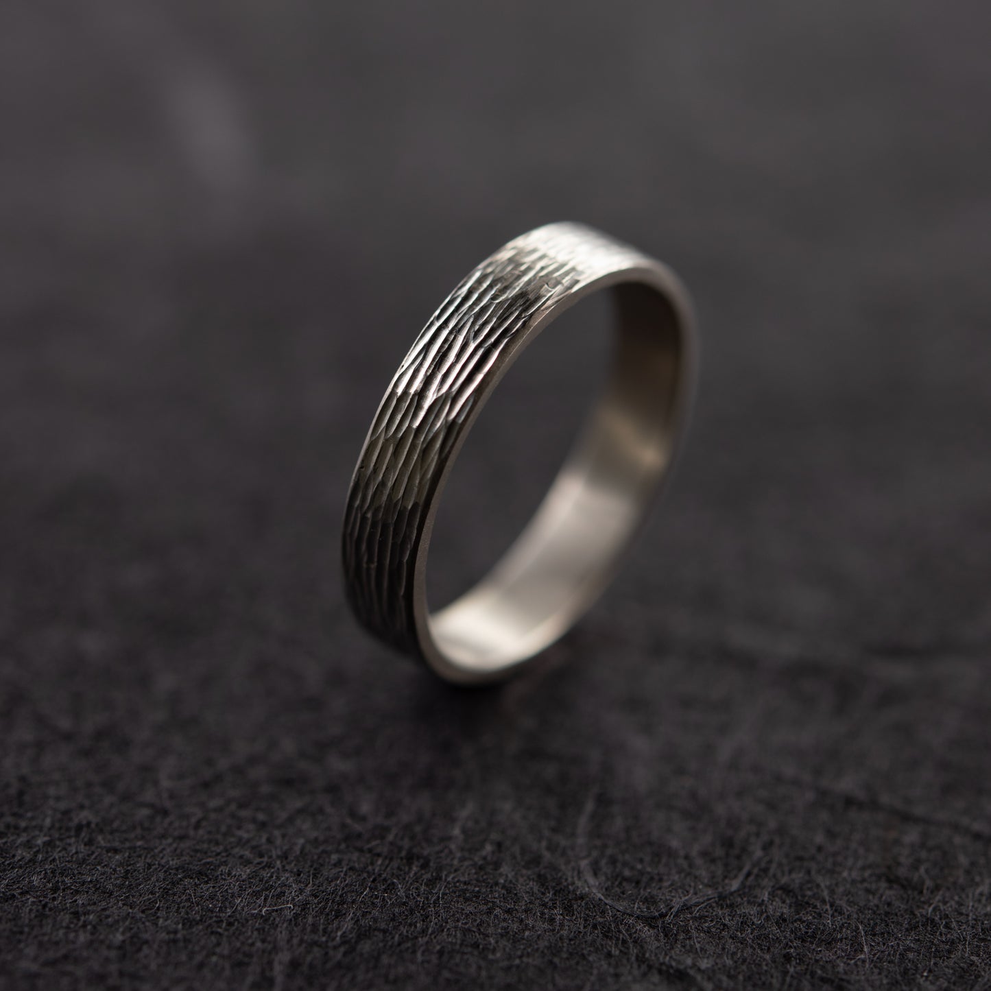 Close-up of textured silver ring on dark background showing engraved surface detail handmade in Paris by AgJc 