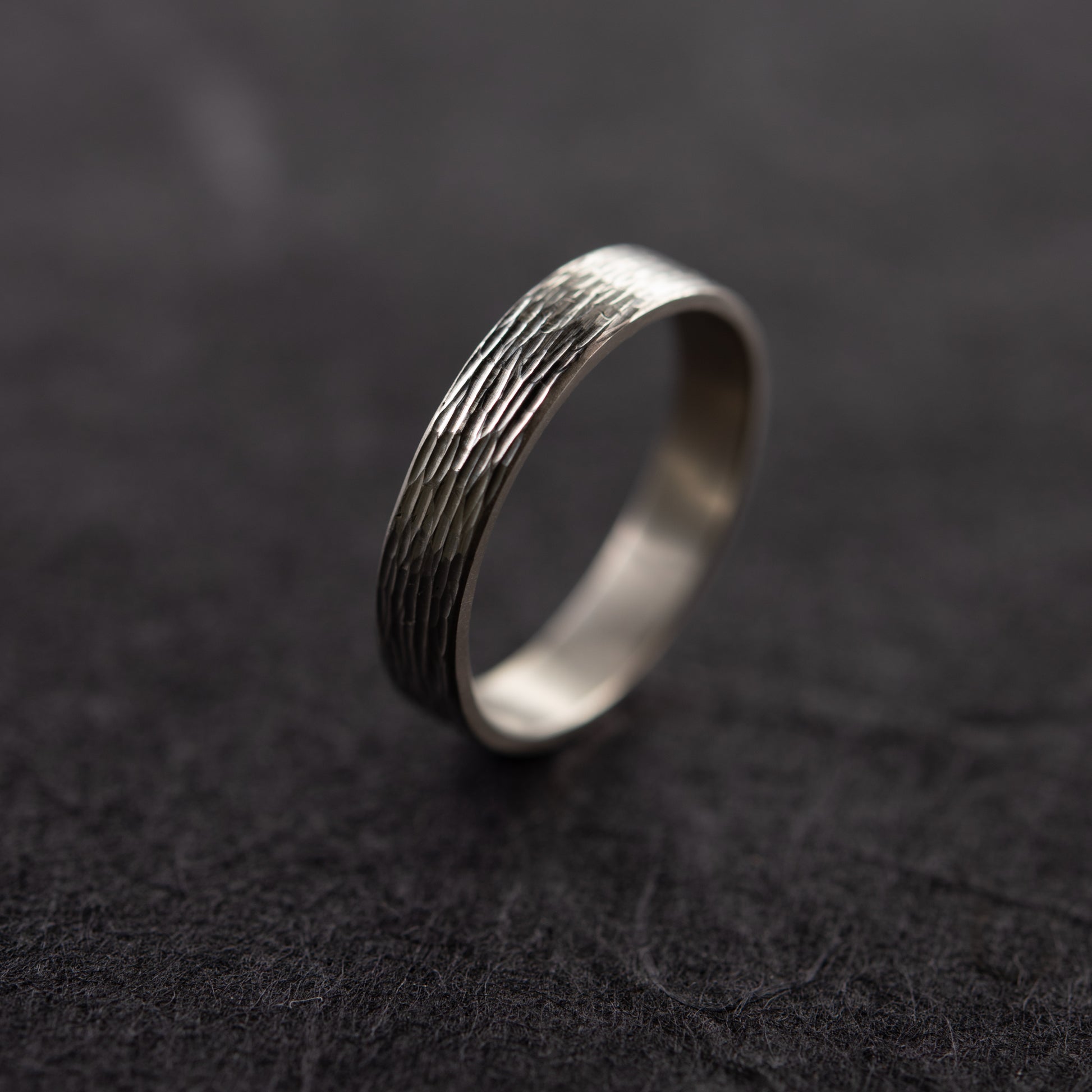 Close-up of textured silver ring on dark background showing engraved surface detail handmade in Paris by AgJc 