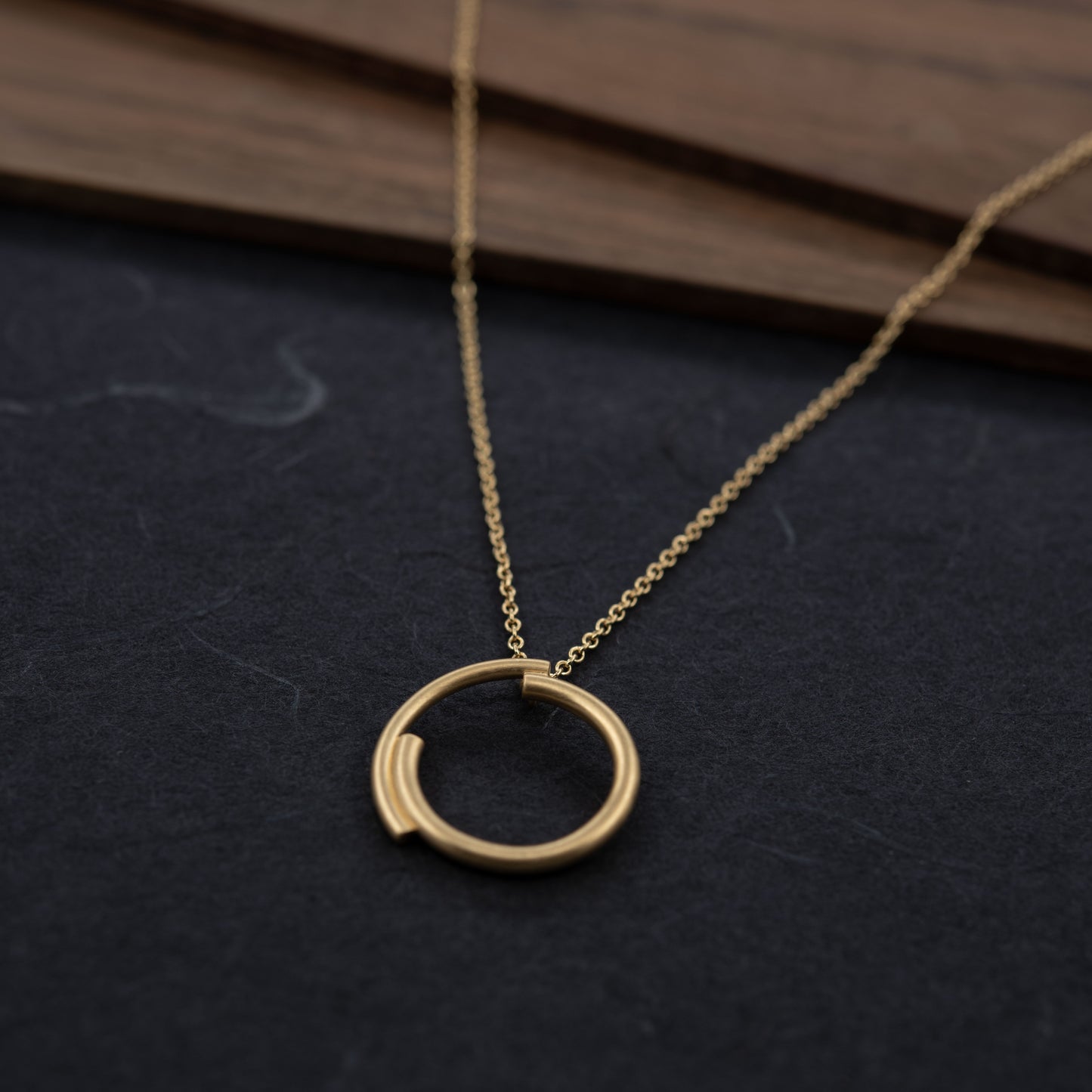Front view of the vermeil circle necklace, photographed on a dark background. Minimalist gold jewelry handmade in Paris.