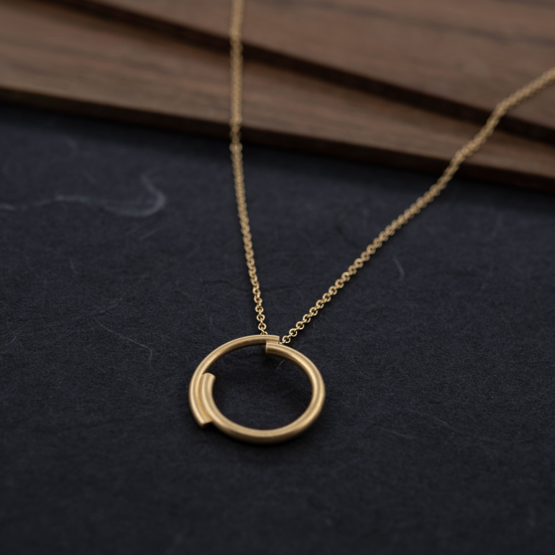 Front view of the vermeil circle necklace, photographed on a dark background. Minimalist gold jewelry handmade in Paris.