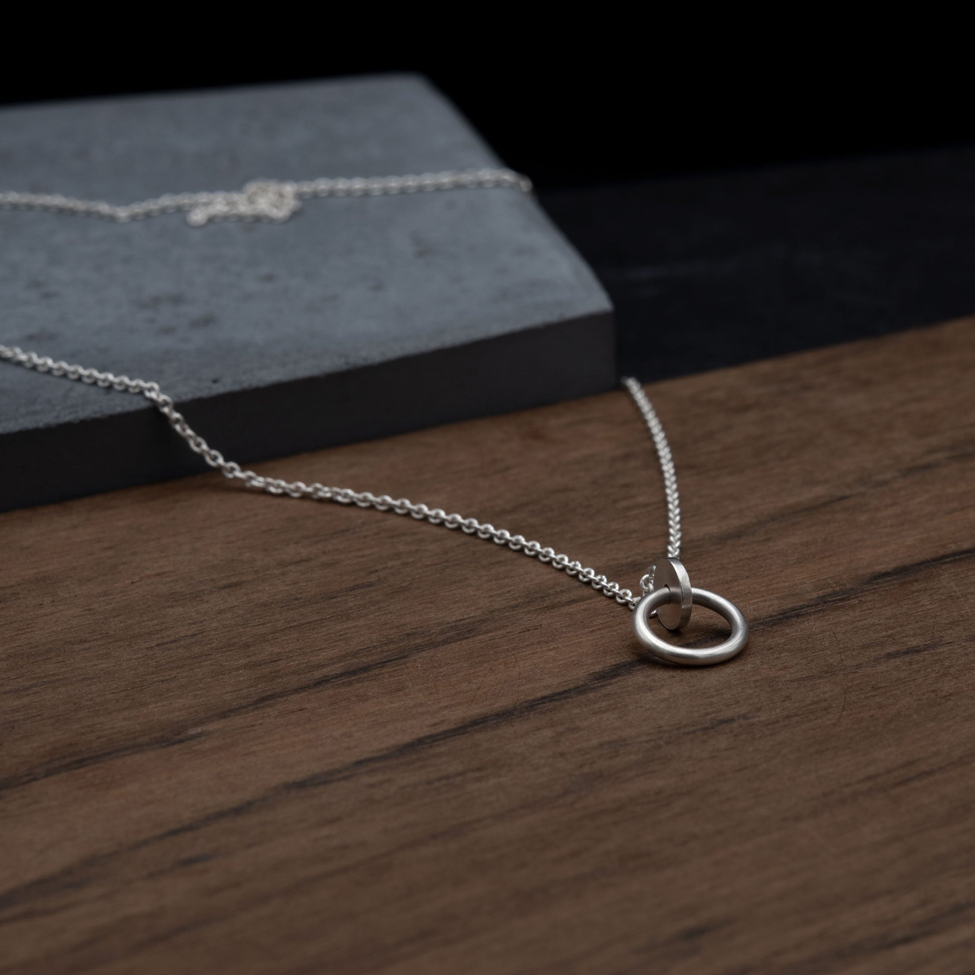 Close up of a circle and dot pendant necklace in sterling silver matte finished