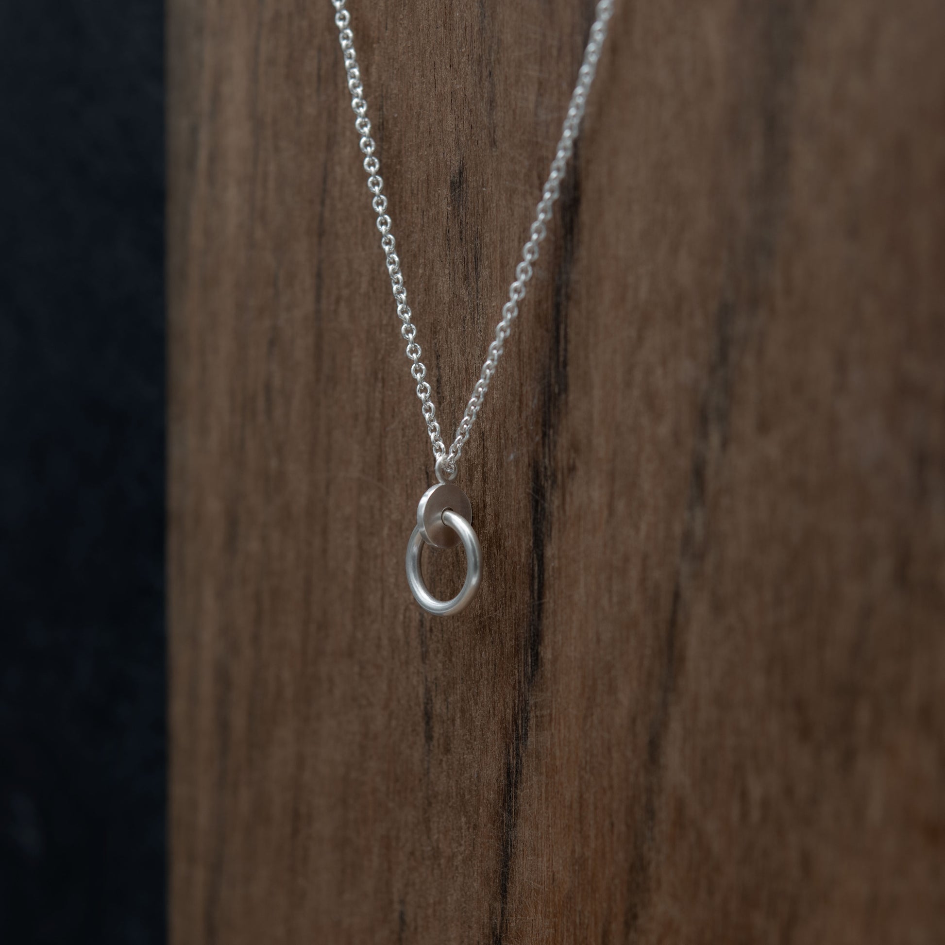 Close up of a circle and dot pendant necklace in sterling silver matte finished