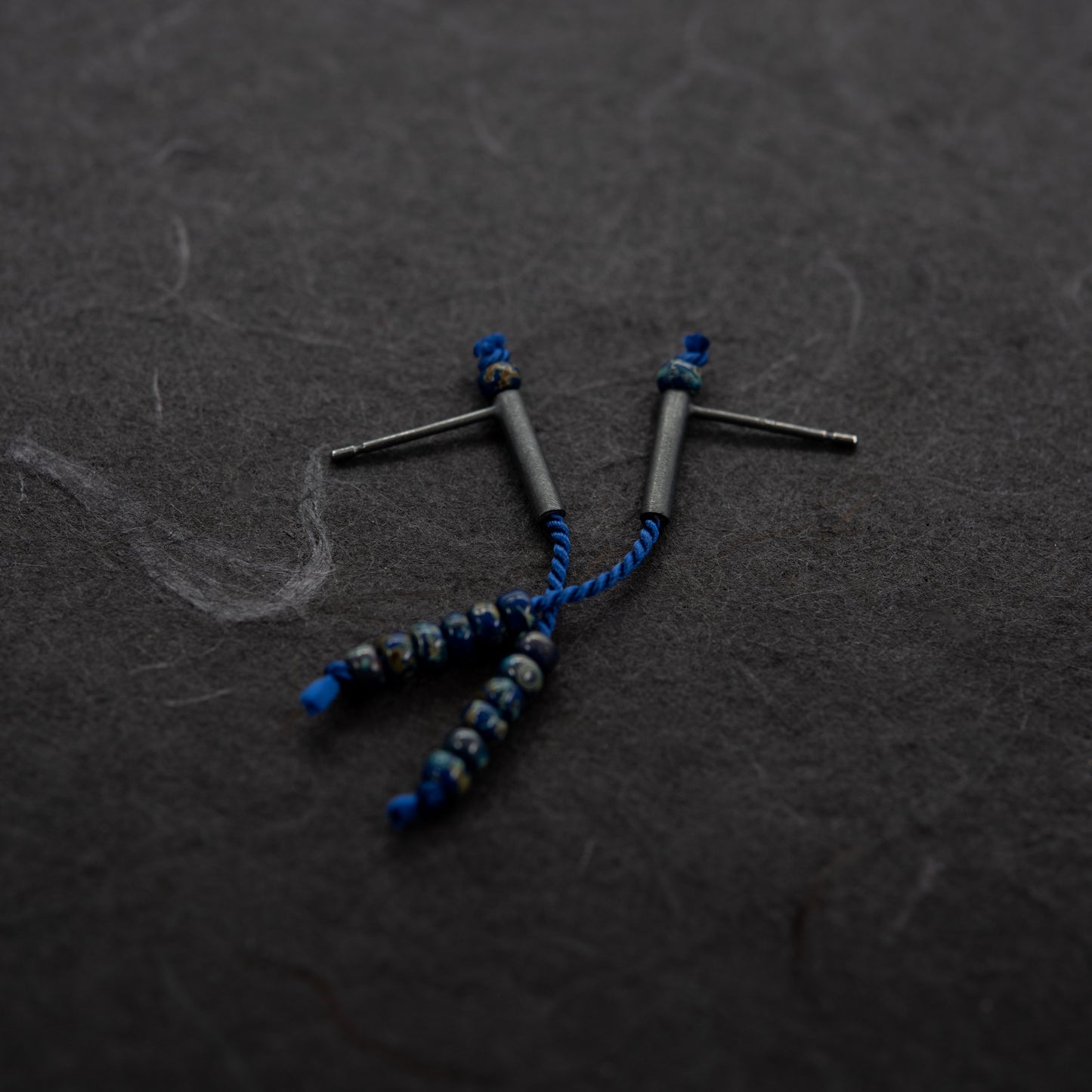 Pair of 38 mm length pendant earrings handmade in oxidized black sterling silver tube with a blue silk cord threaded through the center for hanging Picasso blue Miyuki beads. Designed and made by hand in Paris by A g J c 